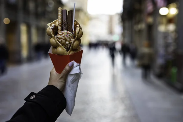 Kadın el dondurma ve şekerler ile bir kabarcık waffle tutan