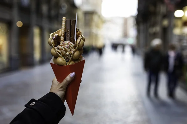 Kadın el dondurma ve şekerler ile bir kabarcık waffle tutan