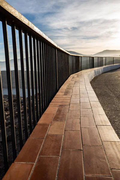 Metalowe i drewniane poręcze na klifie wybrzeża oświetlone światłem zachodu słońca — Zdjęcie stockowe