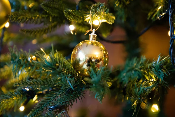Golden decoration globe on christmas tree close up