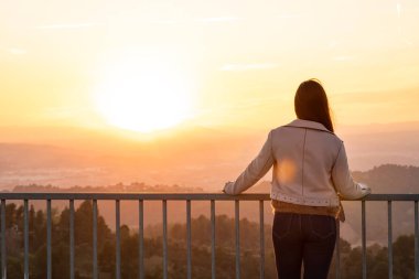 Bulanık arka plan ile gün batımı sırasında bir bakış açısı korkuluk üzerinde güzel kadın geri çekim