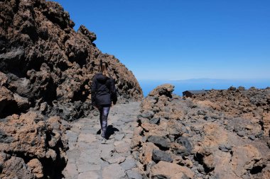 Kuru ve kayalık bir volkanik manzara üzerinde Teide dağ zirvesine yükselen kadın