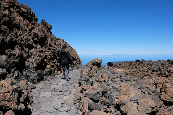 Frau besteigt den Teide-Gipfel in einer trockenen und felsigen Vulkanlandschaft — Stockfoto