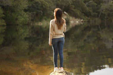 Gölün yakınındaki bir kayanın üzerinde duran kadın