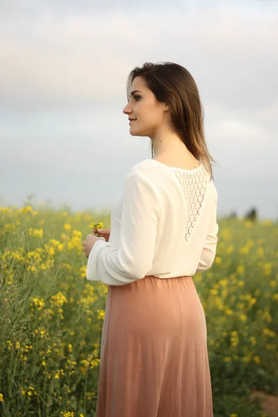 Bella donna su campo di fiori gialli con cielo nuvoloso scuro — Foto Stock