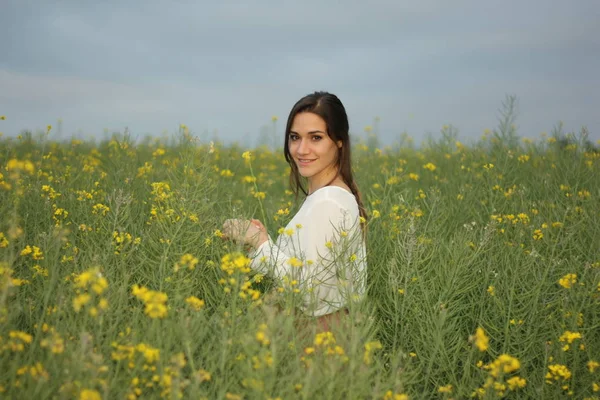 Bella donna su campo di fiori gialli con cielo nuvoloso scuro — Foto Stock