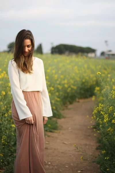 Hermosa mujer en el campo de flores amarillas con cielo nublado oscuro — Foto de Stock