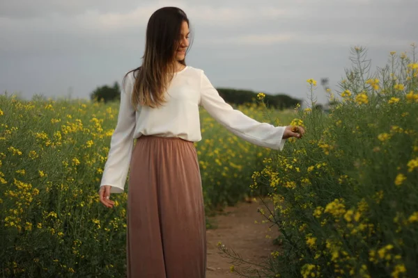 Koyu bulutlu gökyüzü ile sarı çiçekler alanında güzel kadın