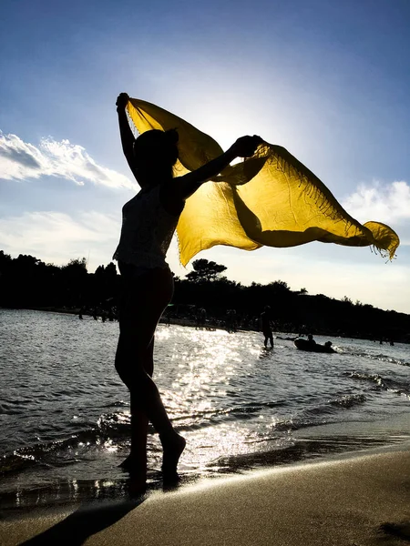 Силуэт девушки с желтым шарфом на закате — стоковое фото