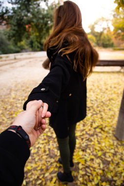 Yere yaprakları ile sonbaharda kadın elini tutan adam