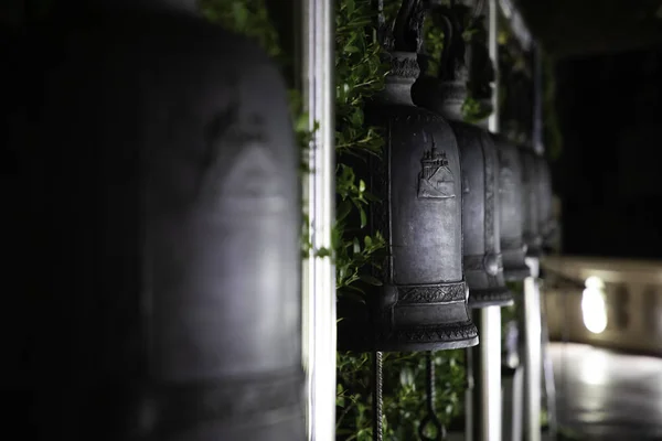 Close up of aligned iron bells in a thai temple at night — Stock Photo, Image