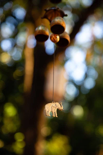 Close up of hanging bells with elephant charm with green leaves in the background — Stock Photo, Image