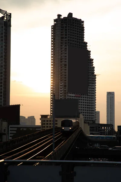 Urban train in Bangkok with building and sunset orange light