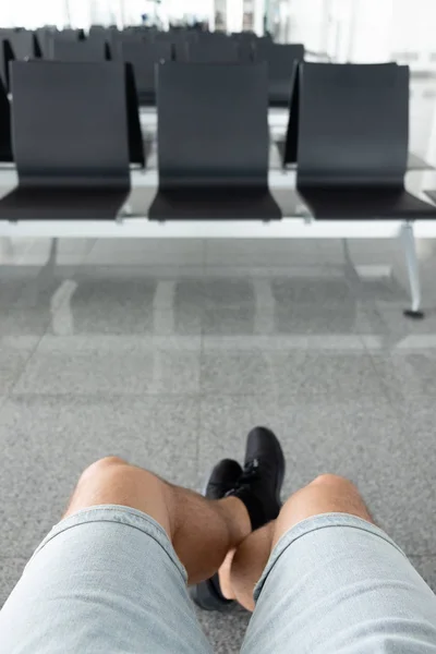 Widok na nogi mężczyzny siedzącego w poczekalni na lotnisku — Zdjęcie stockowe
