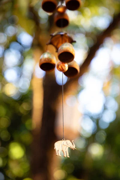 Close up of hanging bells with elephant charm with green leaves in the background — Stock Photo, Image