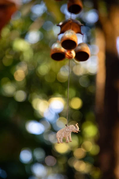 Close up of hanging bells with elephant charm with green leaves in the background — Stock Photo, Image