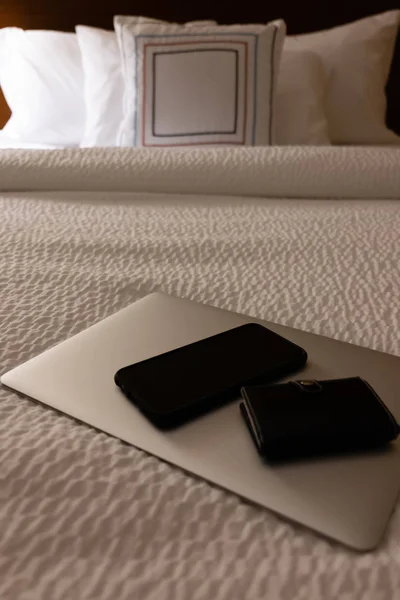 ホテルのベッドでノートパソコン、電話、財布 — ストック写真