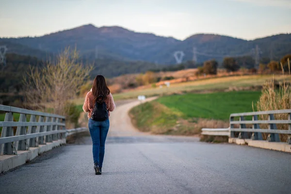 Arka planda bulanık yol ve dağlar ile bir köprü üzerinde güzel kadın yürüyüş