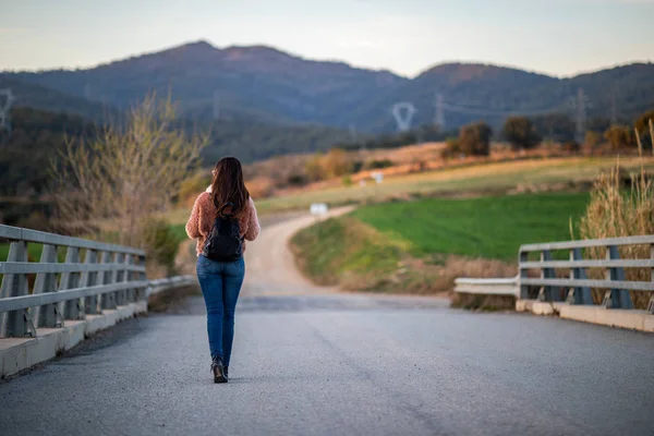 Arka planda bulanık yol ve dağlar ile bir köprü üzerinde güzel kadın yürüyüş