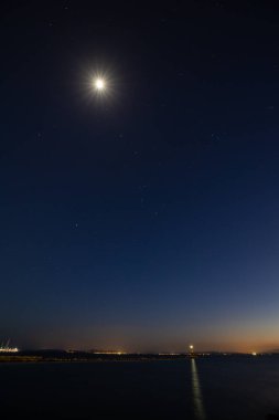 Parlak ay ve deniz üzerinde yıldız ile gökyüzünün gece uzun pozlama