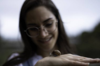 Güzel kadın açık havada elinde bir salyangoz tutarak bulanık