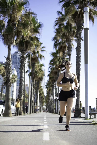 Beautiful woman in sport clothes running on the bike lane at the seafront in Barcelona (SPAIN)