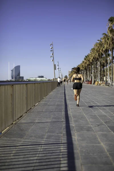 Beautiful woman in sport clothes running on the seafront in Barcelona (SPAIN)