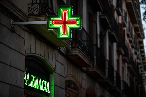 Pharmacy signs illuminated at night on spanish architecture facade