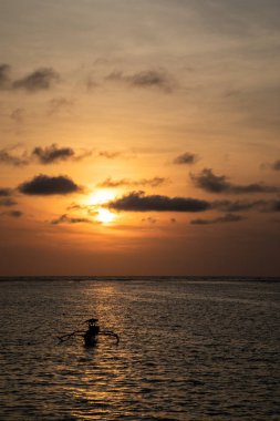 Bali bir tekne ile plaj üzerinde koyu turuncu günbatımı görünümü