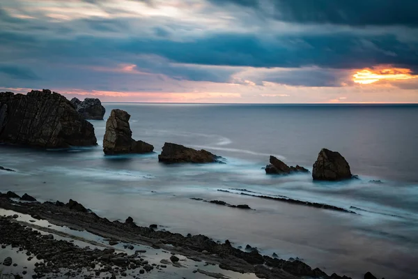 Bulutlu bir günbatımında fotokopi uzayıyla birlikte kayalar ile sakin denizin üzerinde uzun süre durmak