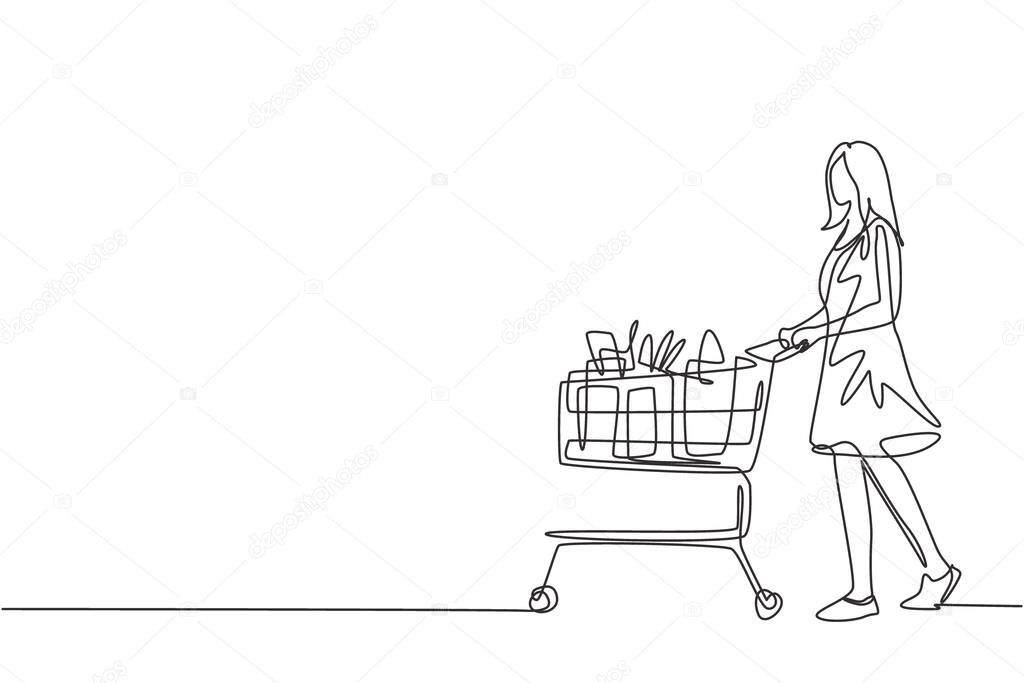 One continuous line drawing young happy female pushing trolley with fruits, bread, milk, vegetables and milk inside. Monthly shopping in supermarket concept. Single line draw design illustration
