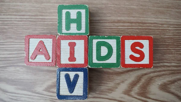 Kelime yardımları ve kahverengi arkaplanda HIV olan tahta küpler. 