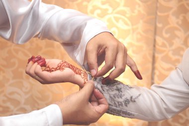 Tören sırasında gelinlerin eline bilezik takan damat