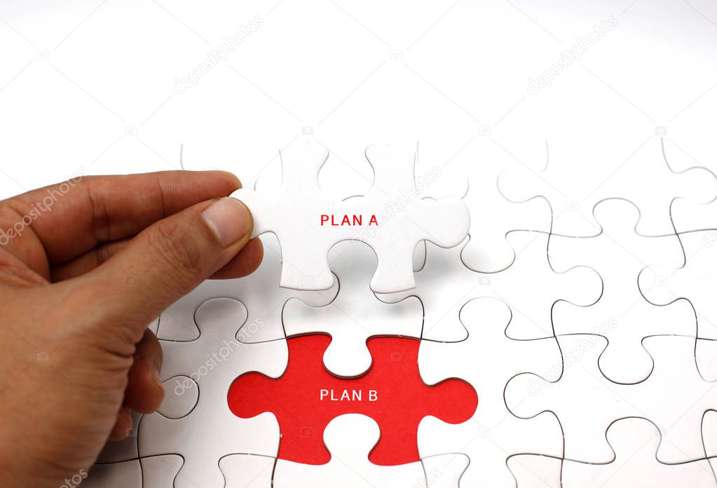 Close up of man holding white jigsaw with text plan A near connected puzzle pieces and empty 