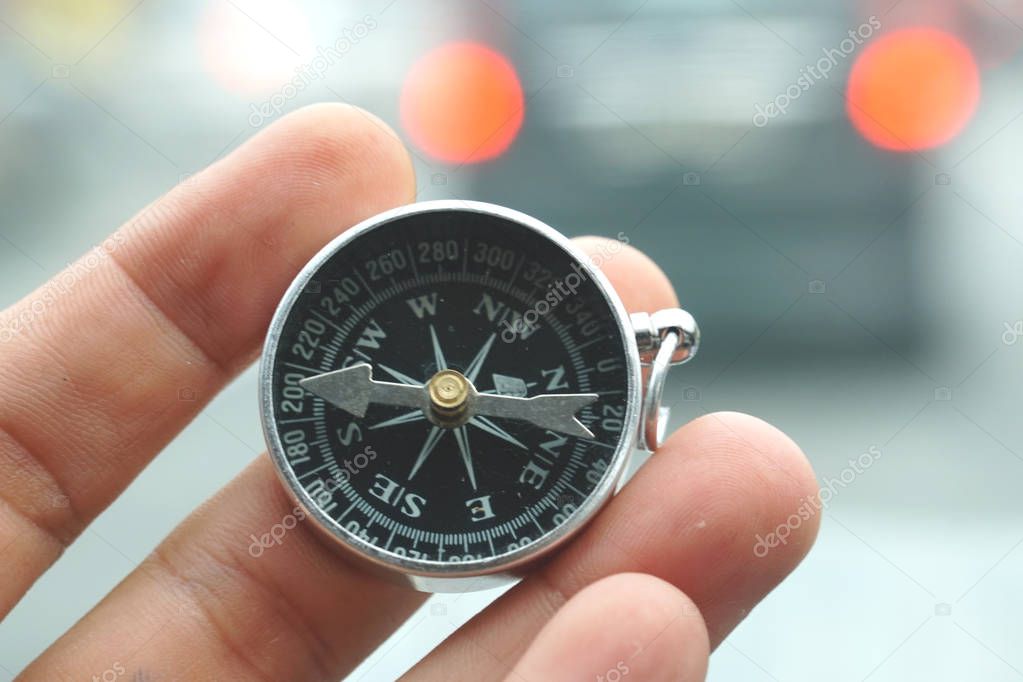 Hand holding a magnetic compass over nature background