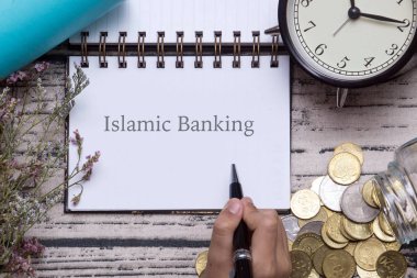 Para ile ahşap arka plan üzerinde İslam bankacılığı yazıt ile not defteri üzerinde Pan tutan erkek el