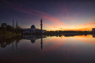 Beyaz yüzen cami üzerinde dramatik bulutlu gündoğumu. Uzun pozlama çekimi nedeniyle yumuşak odaklama. Canlı renkler.
