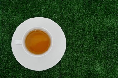 Yeşil çim arka plan üzerinde beyaz fincan taze aromatik çay 