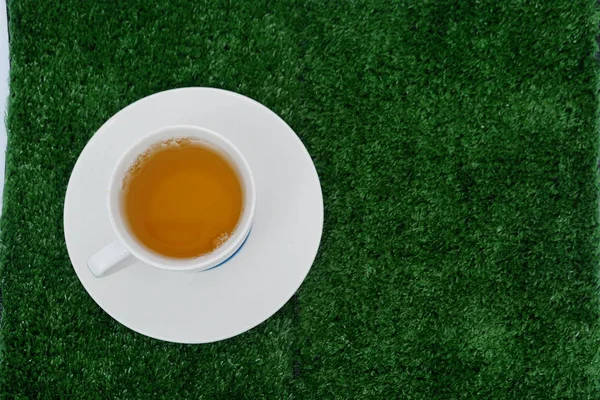 緑の草の背景の上に白いカップで新鮮な芳香茶 — ストック写真