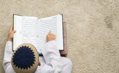 Bej halı üzerinde Coran kitap okuma çocuk üst görünümü 