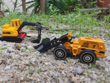 excavators toys machinery on garden ground clipart