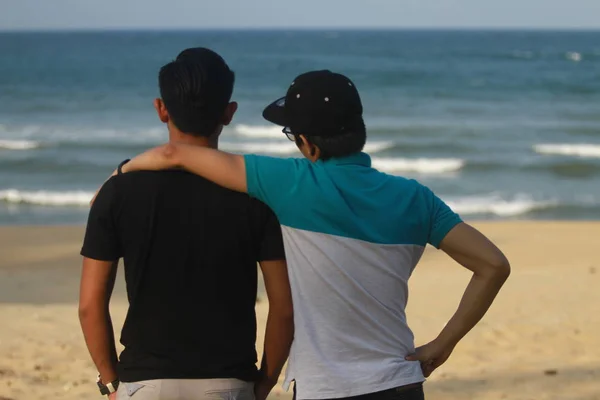 two men standing near ocean