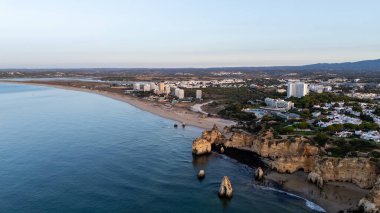 Suyun içinde pürüzlü kayalar olan güzel bir saklanma yeri. Portekiz 'in Algarve bölgesindeki Praia dos Tres Irmaos. Yüksek kalite fotoğraf