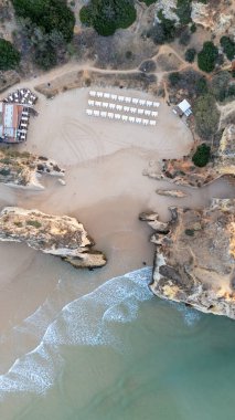 Suyun içinde pürüzlü kayalar olan güzel bir saklanma yeri. Portekiz 'in Algarve bölgesindeki Praia dos Tres Irmaos. Yüksek kalite fotoğraf
