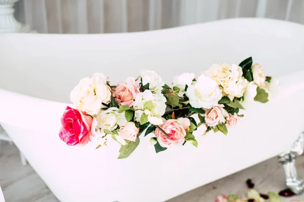 White classical bath with flowers and petals of roses