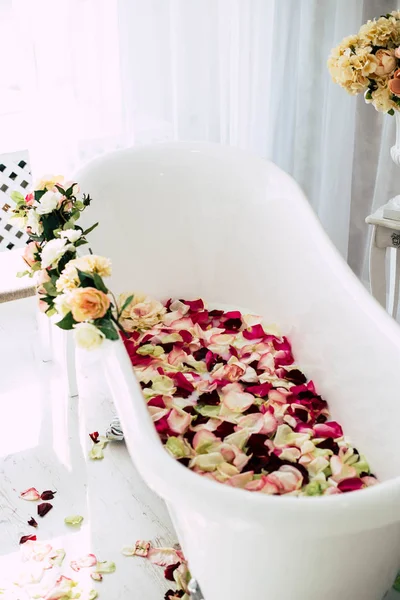 White classical bath with flowers and petals of roses