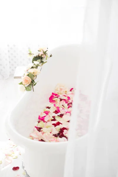 White classical bath with flowers and petals of roses