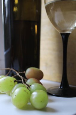 Tahtada şarap şişesi ve cam var.