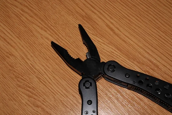 Black multi-tool on a wooden table