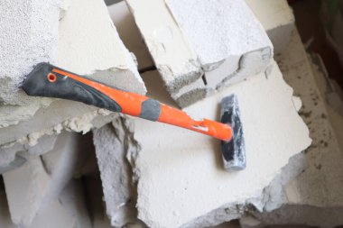 Kırık bir duvarda turuncu çekiç.